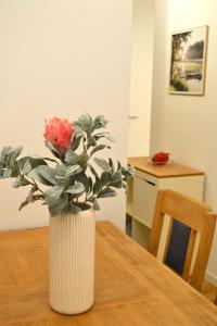 Un jarrón blanco con una rosa rosa sobre una mesa en KomfortPlus modernes Premium Apartment - Top Lage - Balkon - Parkplatz, en Bad Zwischenahn