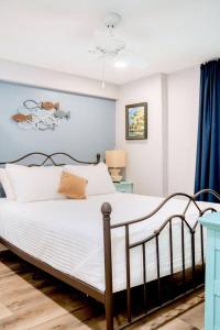 ein Schlafzimmer mit einem weißen Bett mit einer blauen Wand in der Unterkunft Cozy Coastal Cottages of Dunedin 3 in Dunedin