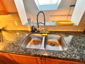 um lavatório de cozinha com uma torneira no balcão em Entire floor in a Spacious bungalow ensuite close to beach and train em Pincourt