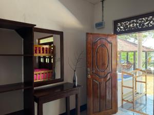 a room with a wooden door and a mirror at kuda Bay Surf Hotel in Arugam Bay