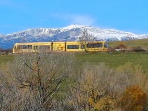un autobús amarillo en un campo con una montaña cubierta de nieve en Le panoramique, en Saillagouse