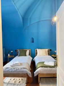 2 letti in una camera con parete blu di B&B Maison Lunarè ad Altamura
