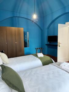 una camera blu con due letti e un lampadario a braccio di B&B Maison Lunarè ad Altamura