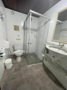 a bathroom with a shower and a toilet and a sink at Pousada Saint Germain in Búzios