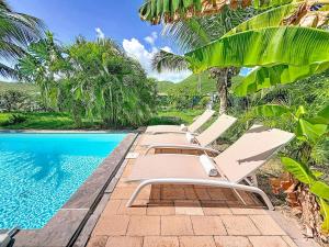 eine Reihe von Liegestühlen neben einem Swimmingpool in der Unterkunft Villa La Note Bleue in Cul de Sac