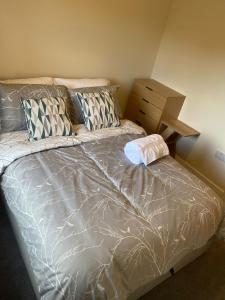 a bed with a gray comforter and pillows at Chimney View Annexe in Wootton