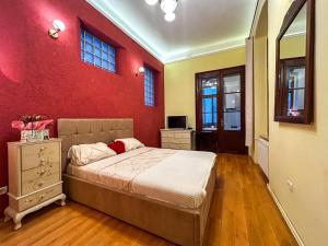 ein Schlafzimmer mit einem Bett und einer roten Wand in der Unterkunft Ada Old Town 7 in Braşov