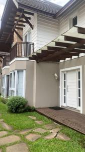 ein Haus mit einer Holzveranda und einem Balkon in der Unterkunft Casa Tranquila - Condomínio Vila Verde Canela in Canela