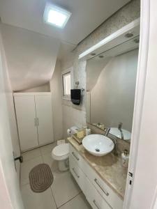 ein Badezimmer mit Waschbecken, Toilette und Spiegel in der Unterkunft Casa Tranquila - Condomínio Vila Verde Canela in Canela