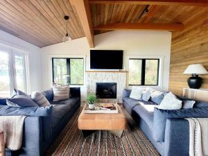 a living room with blue couches and a fireplace at Enetai Beach House with dock and Hot Tub in Point White