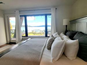 a bedroom with a large bed with a large window at Enetai Beach House with dock and Hot Tub in Point White