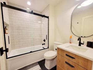 a bathroom with a tub and a toilet and a sink at Enetai Beach House with dock and Hot Tub in Point White +43 photos