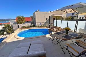 a swimming pool with a table and chairs and an umbrella at Luxury Apartment Ansi in Murter