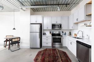 Una cocina con gabinetes blancos y un refrigerador de acero inoxidable. en Chic Double Queen Apt Walking Distance to Fiserv, en Milwaukee