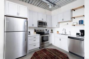 Una cocina con gabinetes blancos y un refrigerador de acero inoxidable. en Chic Double Queen Apt Walking Distance to Fiserv, en Milwaukee