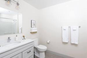 Un baño blanco con inodoro y lavabo. en Chic Double Queen Apt Walking Distance to Fiserv, en Milwaukee