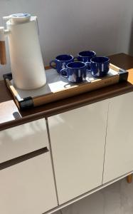 a tray with four blue cups on top of a cabinet at Casa aconchegante no centro da cidade in São Thomé das Letras +1 photo