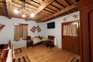 a living room with a table and chairs and a television at Șura lu' Aurel in Gîrdani