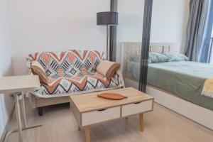 a bedroom with a bed and a couch and a table at Near Central Rama 9 with Balcony, Pool, Gym & 5m to MRT in Bangkok