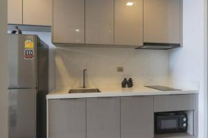 a kitchen with a sink and a refrigerator at Near Central Rama 9 with Balcony, Pool, Gym & 5m to MRT in Bangkok