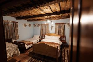 a bedroom with two beds in a room with wooden ceilings at Șura lu' Aurel in Gîrdani