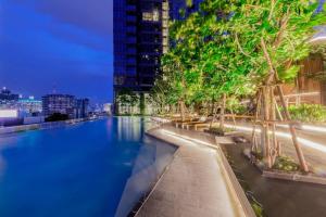a swimming pool with trees on the side of a building at Near Central Rama 9 with Balcony, Pool, Gym & 5m to MRT in Bangkok