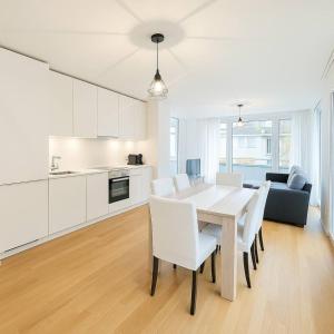 Montchoisi 1 bedroom Near Gare Ouchy Smart Lock في Ouchy: مطبخ أبيض وغرفة طعام مع طاولة وكراسي