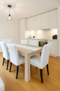 Montchoisi 1 bedroom Near Gare Ouchy Smart Lock في Ouchy: مطبخ مع طاولة خشبية وكراسي بيضاء +3 صور