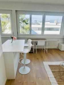 The Minimalist free Parking في Pully: غرفة بها طاولة بيضاء وكراسي ونوافذ +صورة واحدة