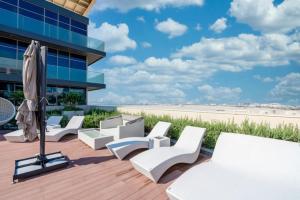 een dek met witte stoelen en een parasol en een gebouw bij Park View Saadiyat Chic 1 BD in Mushayrib