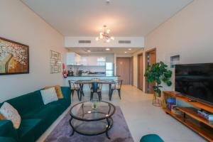 een woonkamer met een groene bank en een tafel bij Park View Saadiyat Chic 1 BD in Mushayrib
