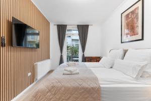 a bedroom with a large white bed with a television on the wall at Elite Weser Apartments in Bremen