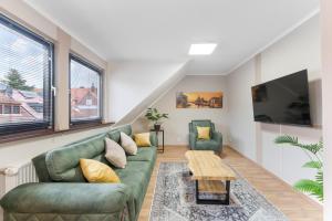 a living room with a green couch and two chairs at Elite Weser Apartments in Bremen