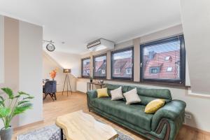 a green couch in a living room with windows at Elite Weser Apartments in Bremen