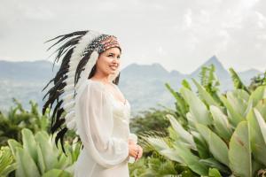 a woman in a white dress with feathers on her head at Cerro Tusa Glamping in Titiribí