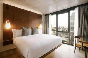 a bedroom with a large white bed and a large window at Merchant LES in New York