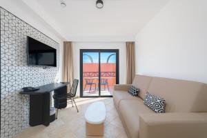 a living room with a couch and a table and a television at Hotel Arena Castillo in Caleta De Fuste