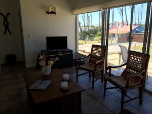 ein Wohnzimmer mit zwei Stühlen und einem Tisch und einem Fernseher in der Unterkunft Nomeolvides Ocean Park Casa in Ocean Park