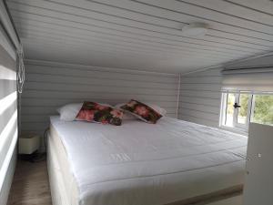 Una cama blanca en una habitación con ventana. en Eco Tiny House, en Algarrobo