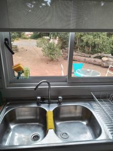 Un fregadero de cocina con una ventana con una esponja encima. en Eco Tiny House, en Algarrobo 2 fotos más