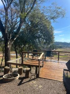 a wooden deck with a picnic table and a tree at chale aster camping santa barbara in Francisco Beltrão