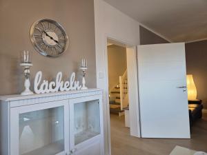 a room with a white cabinet and a clock on the wall at Muttis Haus -Auf dem Felde in Ummern