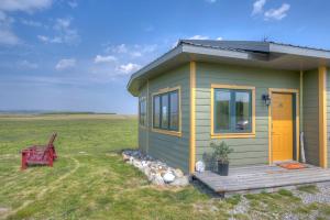 ein kleines grünes Haus mit einer Holzveranda in der Unterkunft Echos and Embers Waterton in Waterton Park