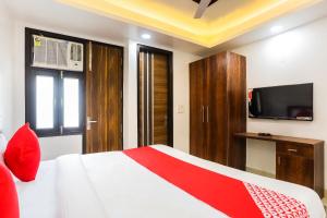 a bedroom with a bed and a tv on the wall at Super Hotel O Kazhakkoottam Near Technopark Phase 3 in Trivandrum +13 photos