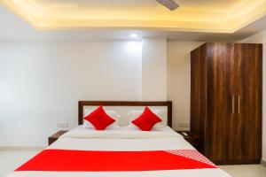 a bedroom with a bed with red pillows at Super Hotel O Kazhakkoottam Near Technopark Phase 3 in Trivandrum