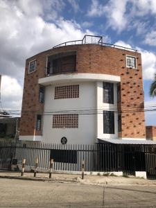 a brick and white building with a black fence at La Curva Apartamentos in Cali