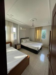 a bedroom with two beds and two windows at Marin Apart Arsuz in Arsuz
