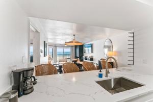 a kitchen and living room with white walls and marble counter tops at Newly Reno Beachfront Escape I Steps to Beach in Clearwater Beach