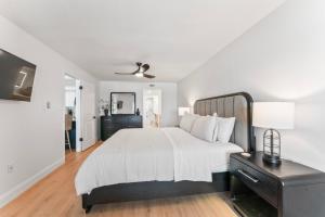 a white bedroom with a large bed and a black dresser at Newly Reno Beachfront Escape I Steps to Beach in Clearwater Beach +44 photos