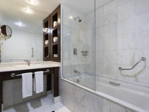 een badkamer met een bad, een wastafel en een douche bij Mercure Sao Paulo Grand Plaza Paulista in Sao Paulo